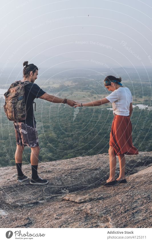 Ein ethnisches Paar von Rucksacktouristen genießt die Freiheit auf einem Hügel genießen Händchenhalten Hipster Backpacker Sonnenuntergang reisen sorgenfrei
