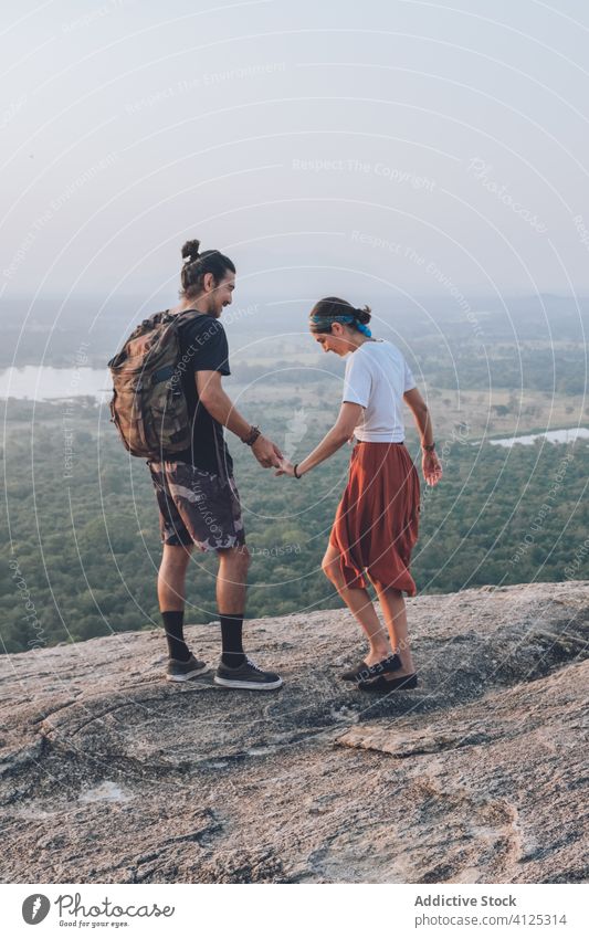 Ein ethnisches Paar von Rucksacktouristen genießt die Freiheit auf einem Hügel genießen Händchenhalten Hipster Backpacker Sonnenuntergang reisen sorgenfrei