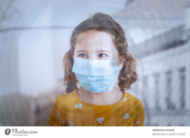 Kleines Mädchen mit medizinischer Maske in der Klinik stehend Mundschutz Krankenhaus besuchen geduldig wenig Gesundheit Pandemie Arzt Seuche behüten Kind