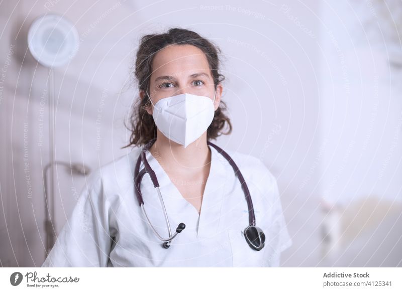Positive junge Ärztin mit medizinischer Maske im Krankenhaus stehend Frau Arzt Uniform Stethoskop Mundschutz Klinik Bund 19 Coronavirus Ausbruch Pandemie Büro