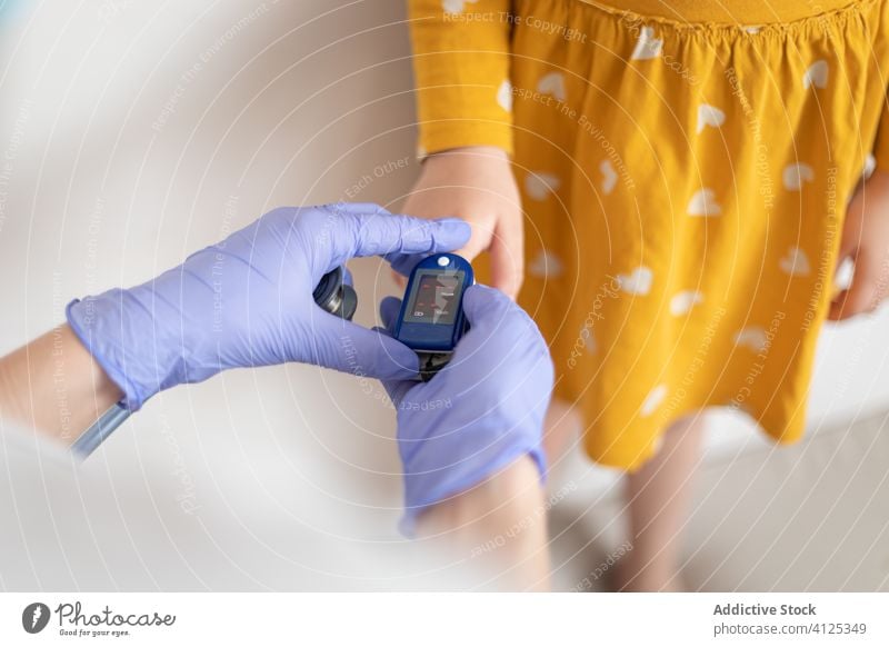Anonymer Arzt mit Latexhandschuhen prüft den Blutdruck eines kleinen Patienten geduldig Druck Manschette Finger Handschuh Mädchen Kleid Klinik Spezialist