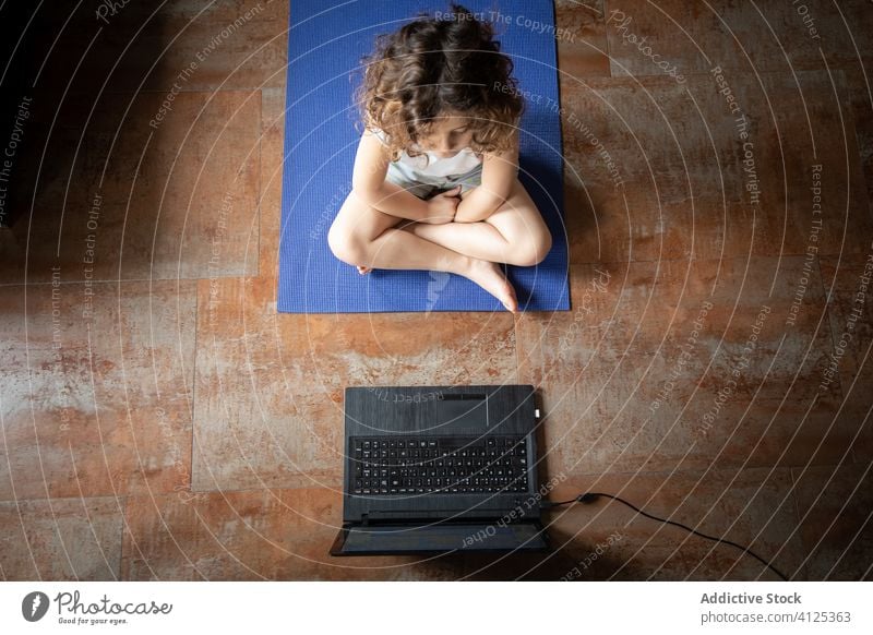 Kleines Mädchen lernt zu Hause online Yoga Kind Laptop üben heimwärts zuschauen Video Tutorial lernen Pose Gerät Apparatur Internet benutzend Unterlage wenig