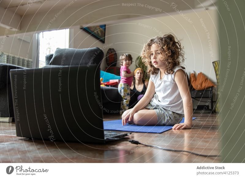 Kleines Mädchen sieht sich während einer Yoga-Sitzung zu Hause ein Video auf dem Laptop an Kind online zuschauen lernen heimwärts üben Tutorial Gerät Apparatur
