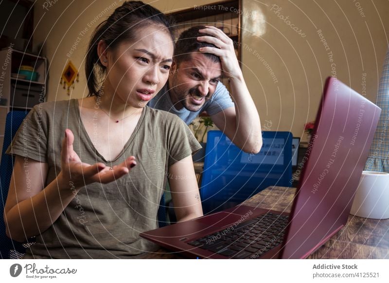 Verwirrtes Paar von Freiberuflern, die zu Hause gemeinsam einen Laptop benutzen verwirren freiberuflich Problematik Projekt Arbeit frustrieren benutzend online