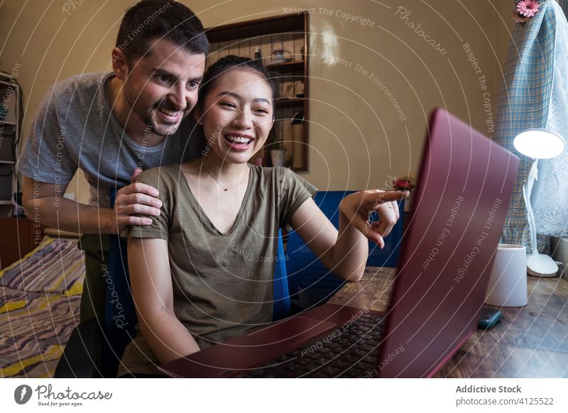 Zwei Freiberufler, die gemeinsam zu Hause einen Laptop benutzen Paar freiberuflich Projekt Arbeit Hilfsbereitschaft benutzend online Glück rassenübergreifend