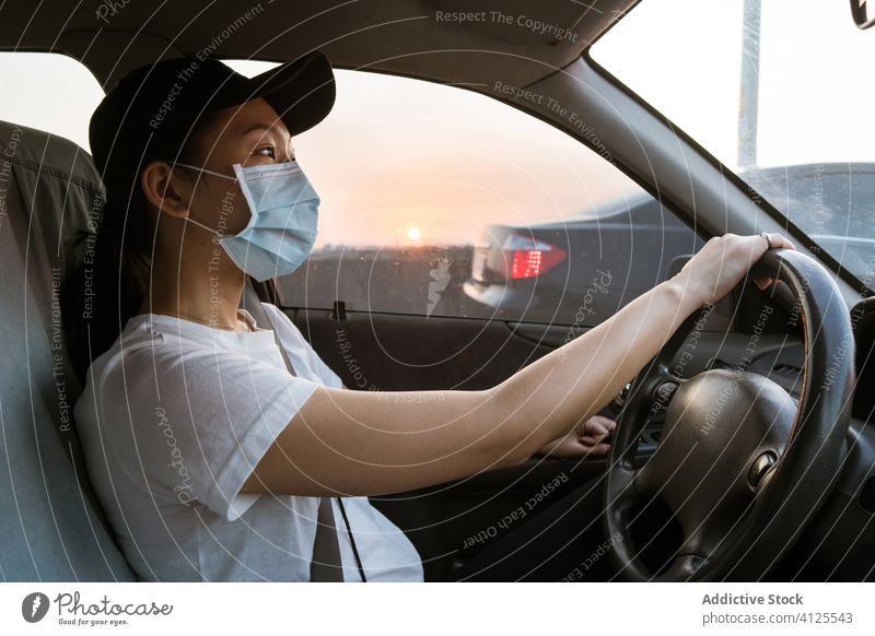 Ethnische Frau mit medizinischer Maske fährt Auto Mundschutz Coronavirus PKW Laufwerk behüten verhindern COVID jung lässig Automobil Ausflug ethnisch asiatisch