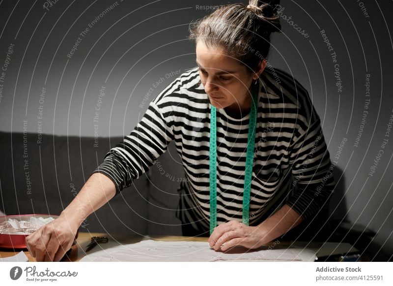 Designer bei der Arbeit mit Stoff auf einem Holztisch zu Hause Frau Gewebe Stapel nähen Stecknadel Muster Detailaufnahme Textil Material Schreibtisch Prozess