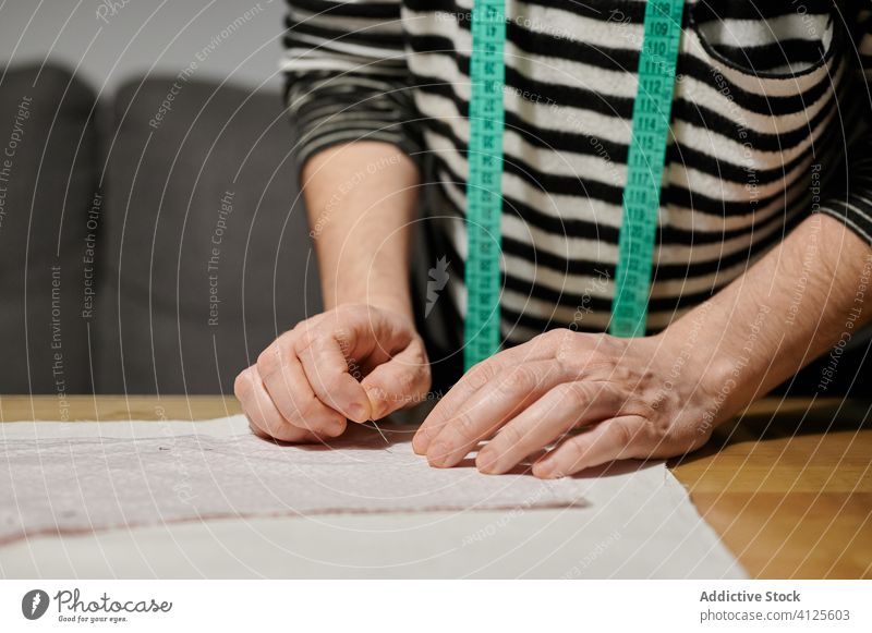 Nicht wiederzuerkennender Pflanzengestalter, der zu Hause mit Stoff auf einem Holztisch arbeitet Frau Designer Gewebe Stapel nähen Stecknadel Muster