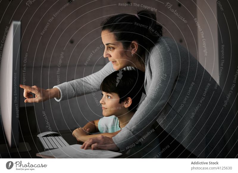 Mutter hilft Kind bei den Hausaufgaben während des Online-Studiums online lernen Bildung Computer Hilfsbereitschaft erklären Zusammensein Mama heimwärts