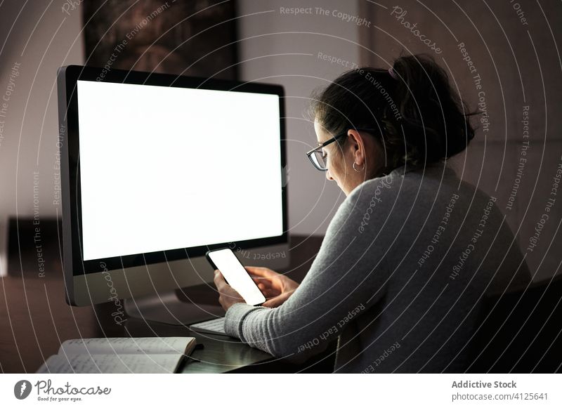 Fokussierte Frau, die zu Hause mit Gadgets arbeitet Arbeit heimwärts Apparatur Smartphone Computer Telearbeit benutzend Browsen jung lässig ernst Konzentration