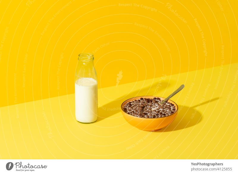 Schokolade Müsli Schüssel und eine Flasche Milch isoliert auf einem gelben Hintergrund. abstrakt Bälle Getränk schwarz Schalen & Schüsseln Frühstück hell braun