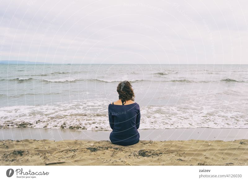 Mädchen sitzt auf dem Sand am Ufer des Strandes mit Blick auf den Horizont des Meeres MEER Hintergrund reisen Textfreiraum traurig Einsamkeit Depression