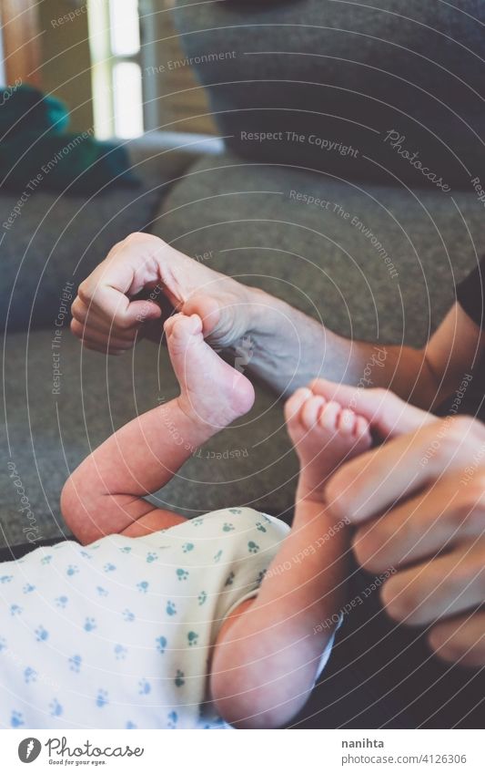 Junger Papa berührt sein Baby Füße verfrüht übungen Beine Gewicht heimwärts neugeboren Neugeborene Säugling Kindheit Fuß Pflege fürsorglich dünn Zehen wenig