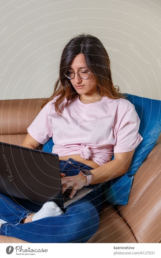 Junge Frauen arbeiten mit Laptop, während sie zu Hause auf dem Sofa sitzen jung anhaben Attrappe T-Shirt lernen Schüler Lifestyle Jeanshose ernst konzentriert