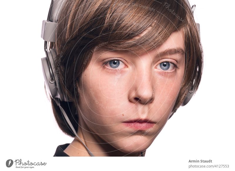 ernst dreinblickender Teenager mit Kopfhörern, isoliert auf weiß Junge männlich gutaussehend fokussiert Konzentration hören Stärke Jugendzeit Musik entschlossen