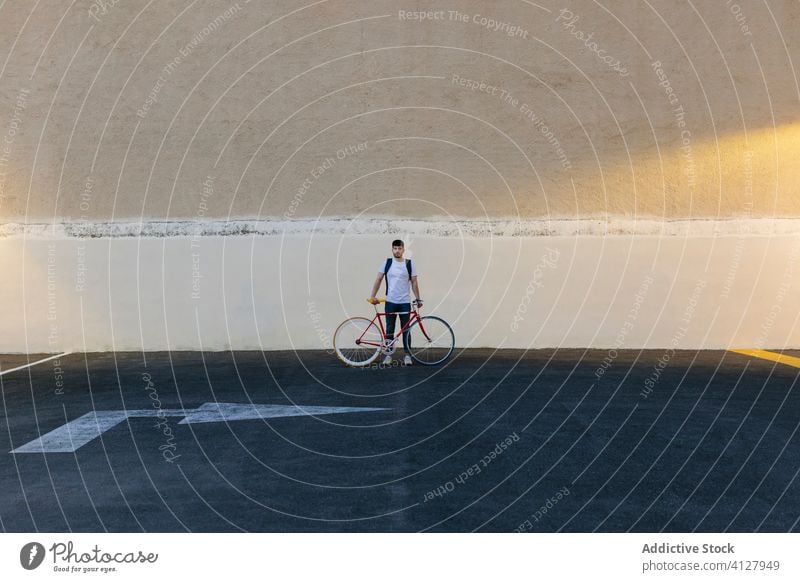 Mann mit Fahrrad in der Mitte eines Parkplatzes Fixie Zyklus urban Rad feststehend Sport Transport Ausrüstung Lifestyle Wand Straße Hipster Mitfahrgelegenheit