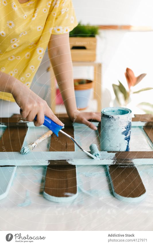 Unbekannte Frau streicht einen Zaun mit hellblauer Farbe Fähigkeit Handwerk Gerät Malerei Bürste Kaukasier Konstruktion Handwerkerin diy es selbst machen blond