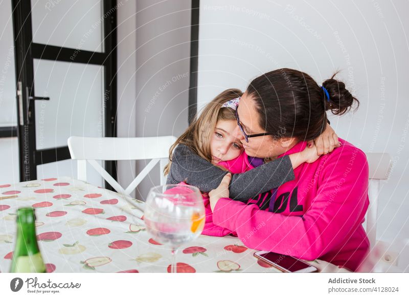 Verärgerte Tochter umarmt Mutter zu Hause Umarmung verärgert abstützen Konsole Windstille heimwärts Liebe lässig Tisch sitzen Mädchen Frau Kind Eltern Brille