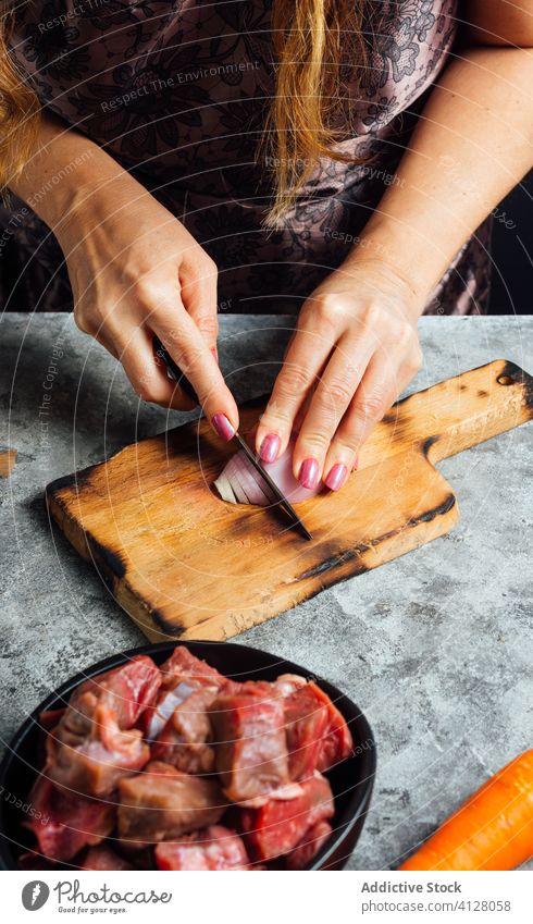Frau schält Zwiebel mit Messer in Küche Hausfrau Gemüse Schürze Würfel Schneidebrett Tisch roh frisch geschnitten Schalen & Schüsseln Fleisch Rindfleisch