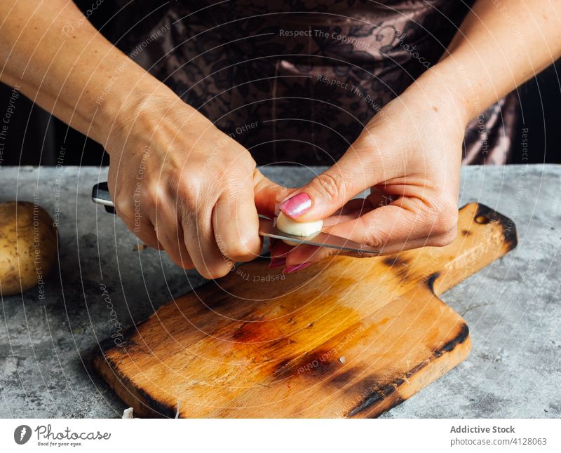 Frau schneidet Knoblauch in der Küche geschnitten Gewürznelke Schneidebrett Messer vorbereiten Koch frisch Tisch Lebensmittel ungekocht kulinarisch Abendessen