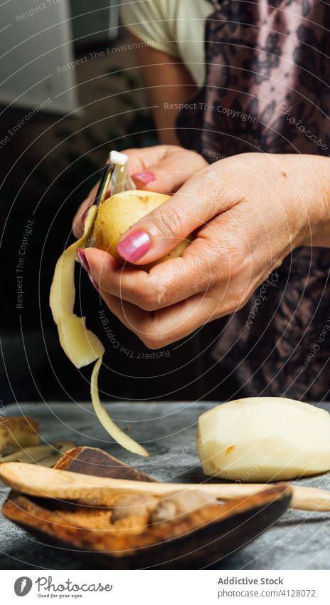 Frau beim Kartoffelschälen in der Küche sich[Akk] schälen Schäler Hausfrau Gemüse Koch Abendessen roh vorbereiten Prozess frisch Tisch stehen Lebensmittel