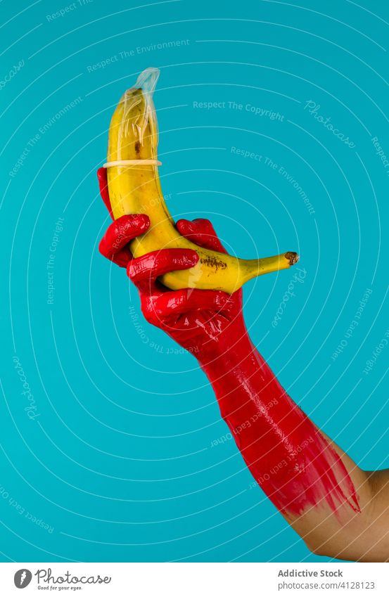 Kondom auf Banane in der Hand der Ernteperson Farbe Latex frisch zeigen Person Frucht sicher Sex Zeitraum HIV Konzept Gummi farbenfroh Verhütung behüten