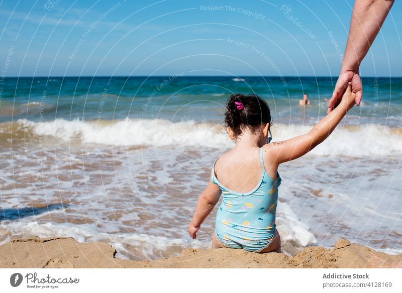 Kleine Tochter und Elternteil halten Hände am Meer Seeküste Strand MEER Badeanzug Mädchen wenig genießen Wasser Meereslandschaft Händchenhalten idyllisch