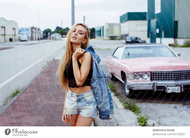 Sinnliches blondes Mädchen steht auf dem Bürgersteig und schaut in die Kamera Frau jung Zopf Sitzen rosa PKW klassisch alt Grunge Sommer Porträt Freizeit urban