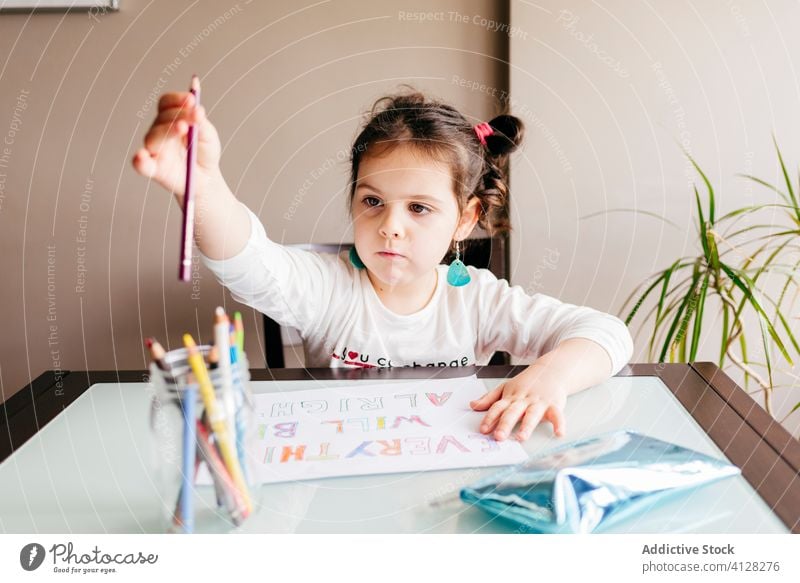 Ernstes kleines Mädchen zeichnet mit Bleistift auf Papier zu Hause Fokus Zeichnung klug Vorschule lernen Erziehung entwickeln Kind Hobby Kunst Tisch heimwärts