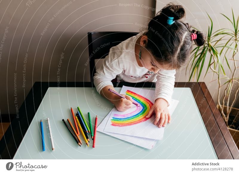 Mädchen zeichnet Bild auf Papier am Tisch zu Hause Zeichnung Regenbogen Bleistift kreativ Optimist positiv farbenfroh hell Inspiration Kind Kunst Farbe zeichnen