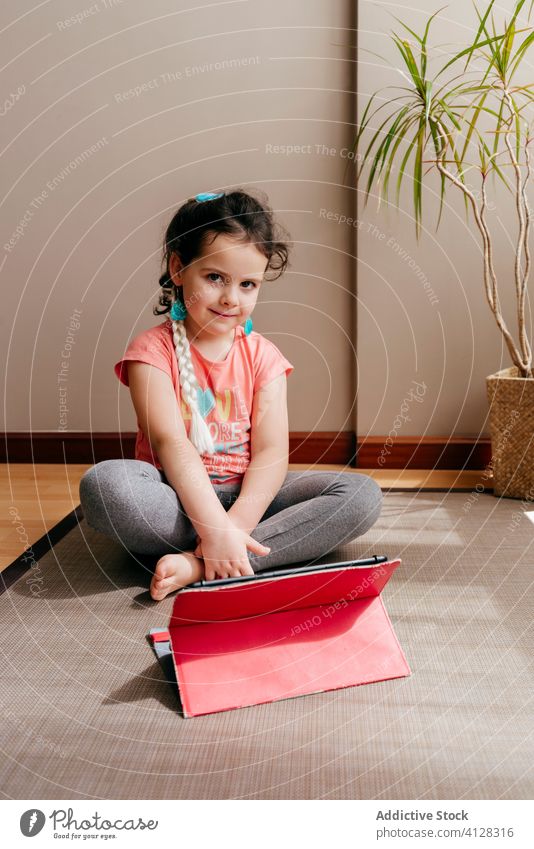 Kleines Mädchen ruht sich nach Yoga im hellen Raum aus ruhen Kind Unterlage Video Tablette sitzen Tutorial üben zu Hause Stressabbau zuschauen Fokus Harmonie