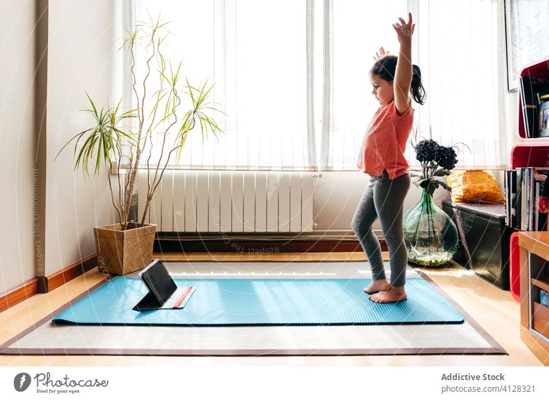 Kleines Mädchen übt Yoga in Berghaltung Kind Asana üben heimwärts Berg-Pose Tablette online tadasana beweglich Dehnung wenig Unterlage Gleichgewicht
