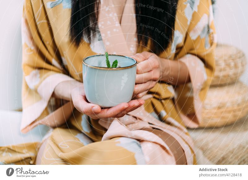 Junge Frau hält Minztee zu Hause in der Hand sich[Akk] entspannen trinken heiß Minze Getränk Becher Tee genießen Morgen frisch lecker warm Komfort lässig
