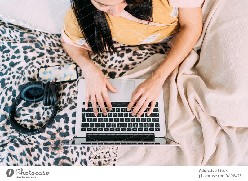 Frau mit Laptop und Kopfhörern auf dem Bett arbeiten Tippen Musik zuhören Kälte Glück genießen Komfort räkeln Schlafzimmer sich[Akk] entspannen Lifestyle ruhen