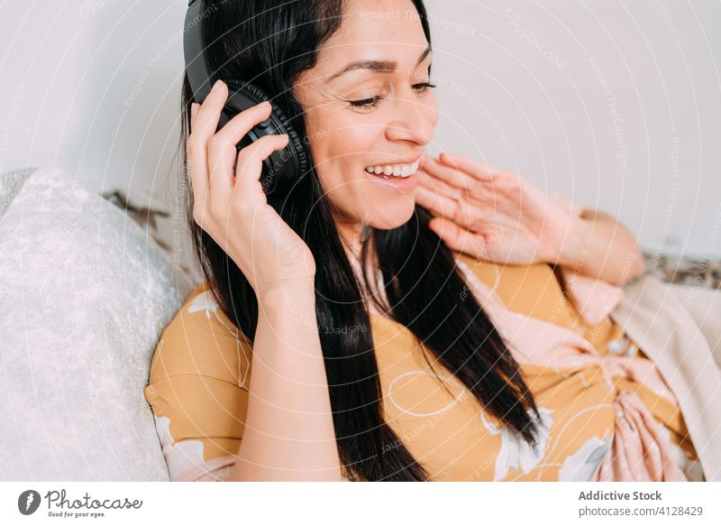 Glückliche Frau hört Musik mit Kopfhörern auf dem Bett zuhören Kälte genießen Komfort räkeln Schlafzimmer sich[Akk] entspannen Lifestyle ruhen Apparatur Gerät