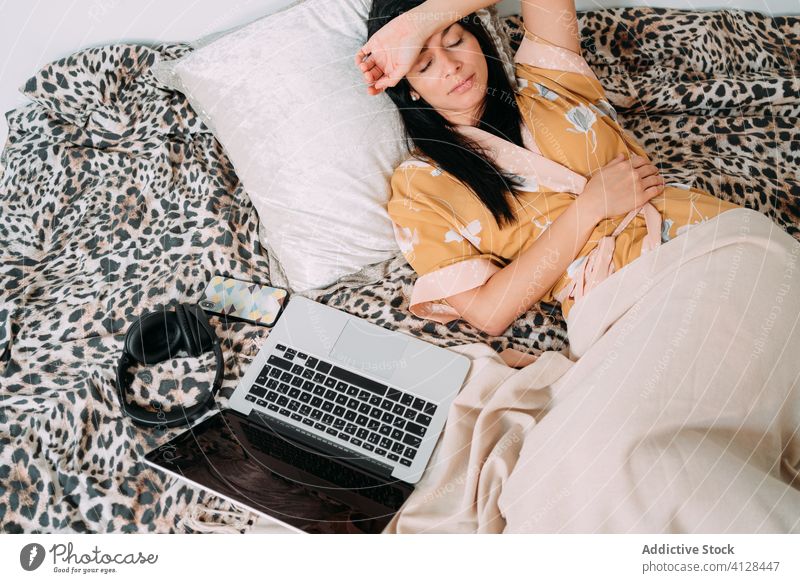 Frau ruht sich mit Laptop und Kopfhörern auf dem Bett aus Musik zuhören Kälte Glück genießen Komfort räkeln Schlafzimmer sich[Akk] entspannen Lifestyle ruhen