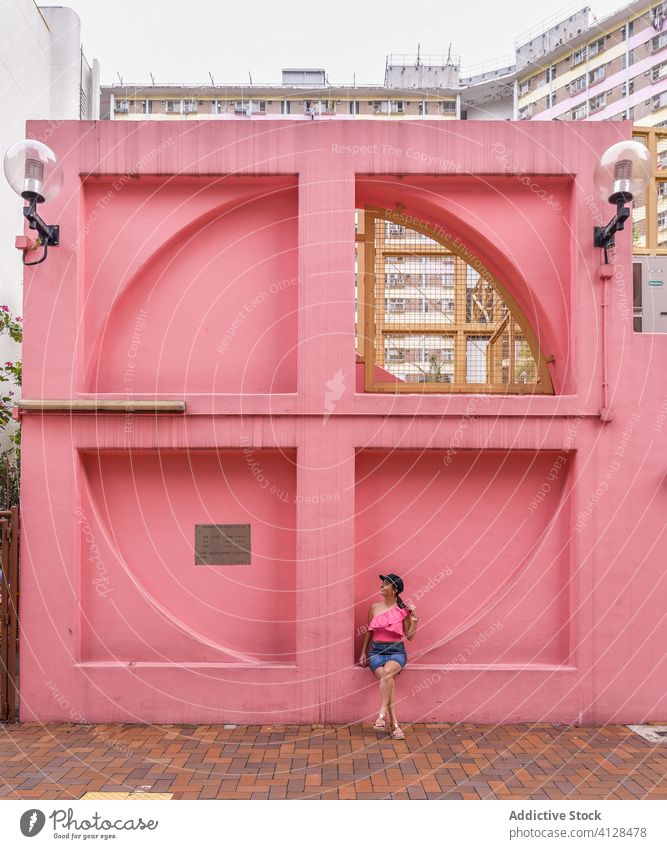 Frau in der Nähe einer kreativen Stadtinstallation in Hongkong Großstadt Außenseite Revier rosa Wand Sommer Fenster Installation Form ungewöhnlich Viertel
