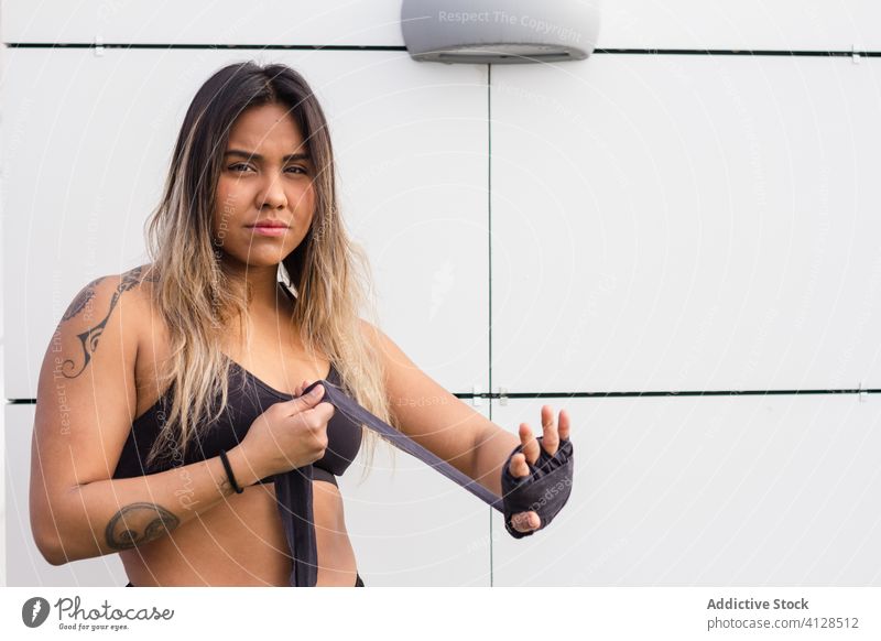 Konzentrierte ethnische Kämpferin in Bandagen bandagieren umhüllen Sportlerin Training brutal Konzentration Straße behüten Boxer Fokus Frau mma BH
