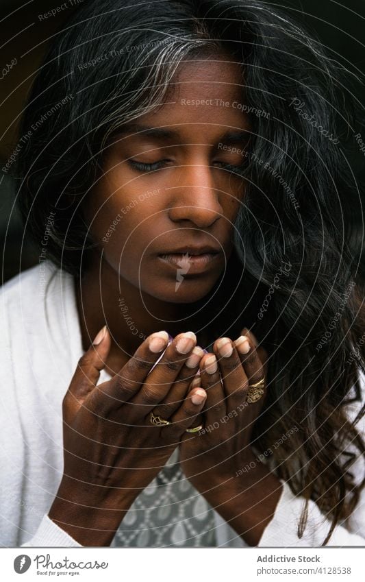 Ruhige ethnische Frau riecht Parfüm auf Händen Duftwasser riechen Aroma Hand ruhig angenehm genießen Porträt inhalieren Inder hinduistisch Windstille