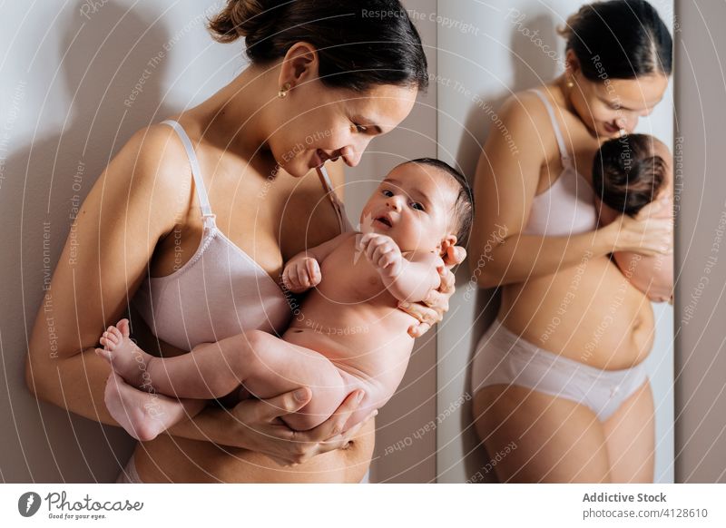 Fröhliche Mutter und Kleinkind im Wohnzimmer Säugling kuscheln Unterwäsche Baby heiter Freude Lächeln Spiegel Zusammensein Mama Mutterschaft Eltern Elternschaft