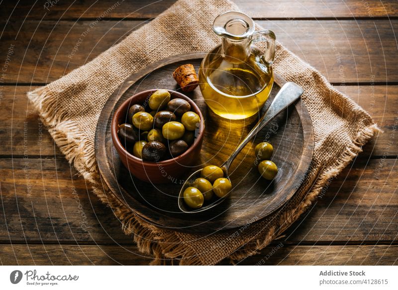 Öl in Glasflasche und Oliven im Löffel auf dem Tisch oliv Erdöl Flasche extra jungfräulich hölzern Teller Kannen Schalen & Schüsseln Küche Karaffen Geschirr