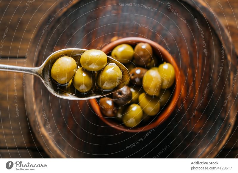 Löffel mit Oliven in Öl in der Küche oliv Erdöl Schalen & Schüsseln Tisch Keramik hölzern Teller extra jungfräulich Geschirr Küchengeräte grün Feinschmecker