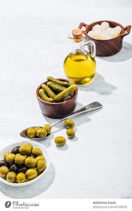 Schalen mit Snacks und Glasgefäß mit Olivenöl oliv Erdöl Pickles Schalen & Schüsseln Salatgurke Tisch Reihe eingelegt extra jungfräulich Kannen Löffel Küche