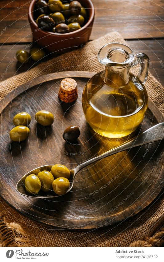 Öl in Glasflasche und Oliven im Löffel auf dem Tisch oliv Erdöl Flasche extra jungfräulich hölzern Teller Kannen Schalen & Schüsseln Küche Karaffen Geschirr