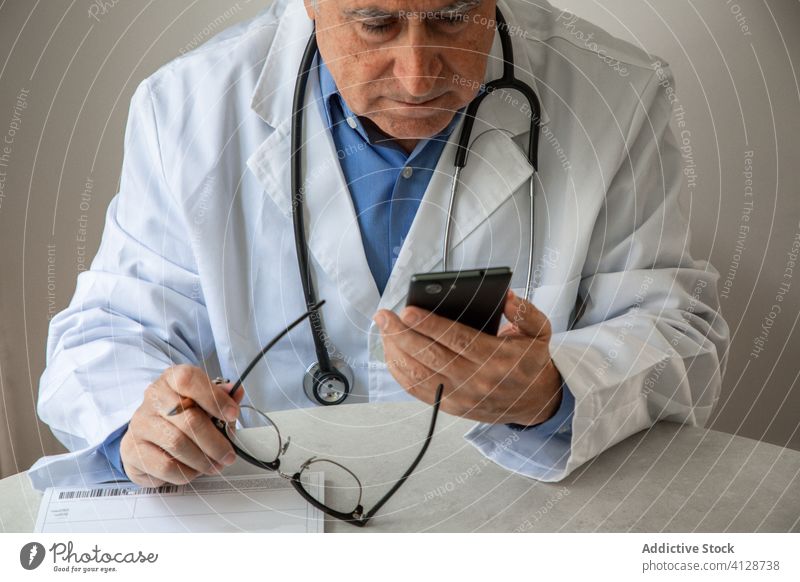 Leitender Arzt berät Patientin online während der Quarantäne Telemedizin konsultieren Mann Senior Coronavirus Smartphone Videoanruf benutzend männlich älter