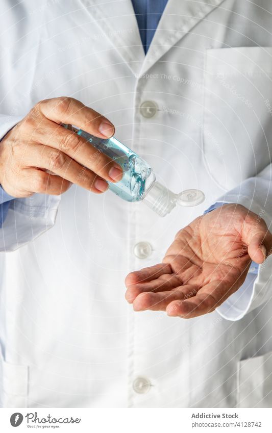 Männlicher Arzt desinfiziert seine Handflächen mit einem Antiseptikum im Krankenhaus desinfizieren antiseptisch antibakteriell Mann Klinik Coronavirus Pandemie