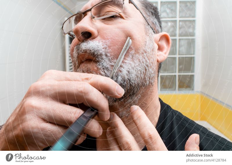 Bärtiger Mann beim Rasieren mit Rasiermesser Rasur Rasierer gerade Vollbart reif Bad Verfahren Hygiene Pflege klassisch Messer altehrwürdig männlich Lebensmitte