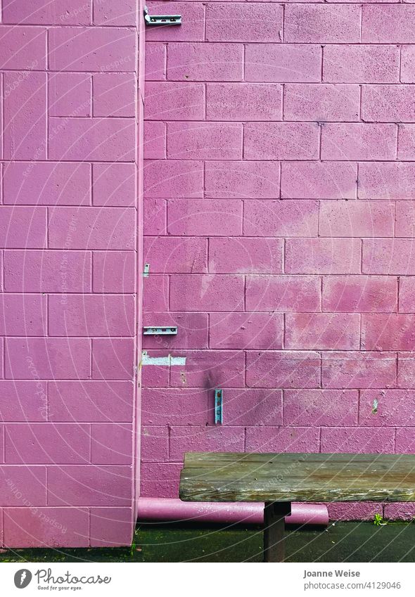 Rosa Ziegelwand mit braunem Sitz. rosa rosa Hintergrund rosa Wand grobkörnig Backsteinwand Baustein Sitzgelegenheit Außenaufnahme Mauer Fassade alt
