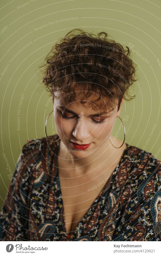 Porträt einer nach unten schauenden Frau Erwachsener schön Schönheit Freizeitkleidung Selbstvertrauen selbstbewusst Kräusel krause Haare Ohrringe Vorderansicht