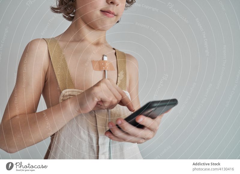 Gadget-abhängiger Junge mit Ladekabel an Smartphone angeschlossen Apparatur Ladedraht kleben verputzen Süchtige Kind benutzend Konzept kreativ Browsen
